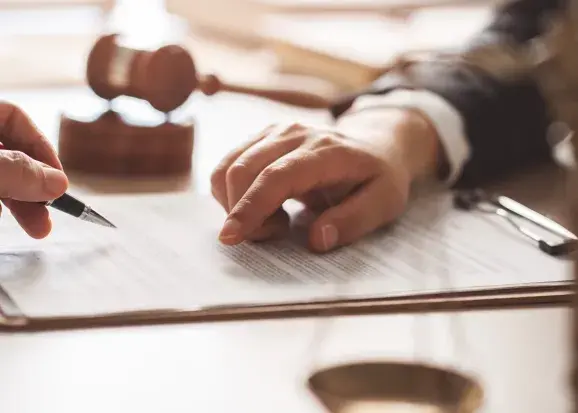 Scène de signature d'un document, une main indiquant un endroit et une autre main tenant un stylo